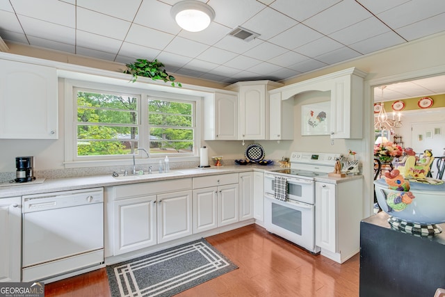 kitchen with a sink, white appliances, light countertops, light wood-style flooring, and visible vents