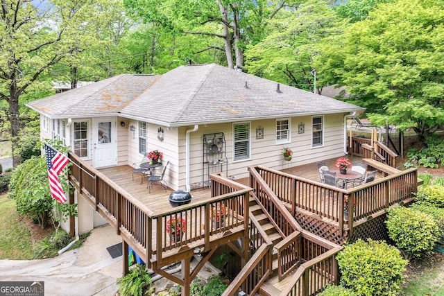 rear view of house featuring a shingled roof, a wooden deck, and stairway