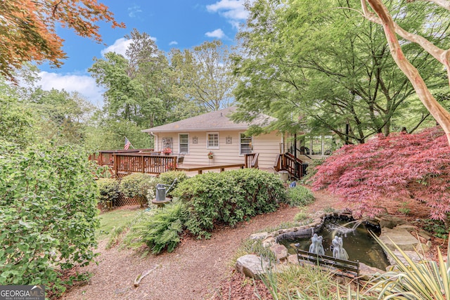 view of yard featuring a wooden deck and a garden pond