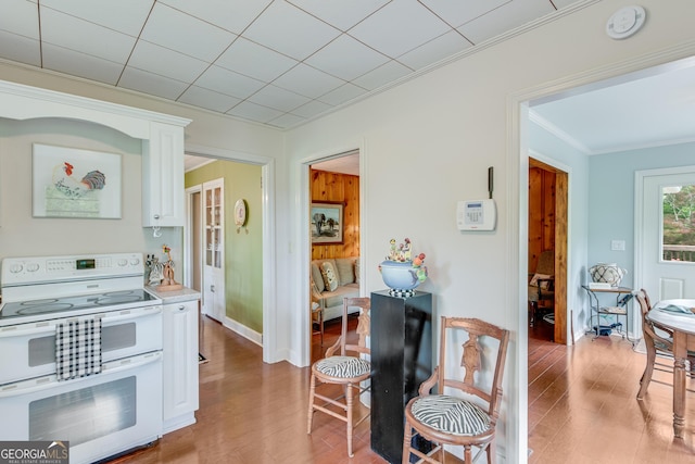 kitchen featuring double oven range, crown molding, light countertops, white cabinets, and light wood-style floors