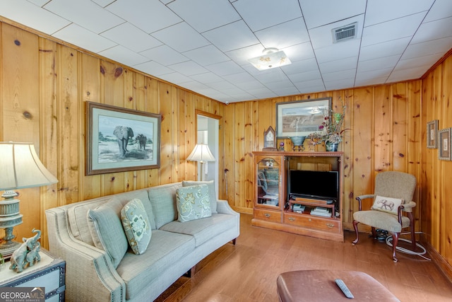 living room with wood walls, wood finished floors, and visible vents
