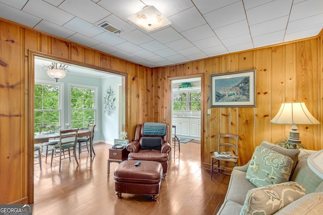living room featuring wood walls, a healthy amount of sunlight, visible vents, and wood finished floors