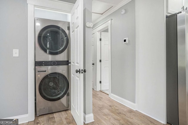 581 Taylor Dr SE, Smyrna, GA 30080 - laundry room featuring stacked washer and dryer, laundry area, light wood-style flooring, baseboards, and ornamental molding