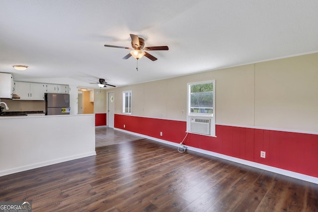 unfurnished living room with dark wood-style flooring, a sink, a ceiling fan, baseboards, and vaulted ceiling