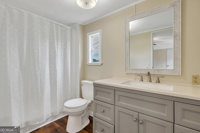 full bathroom featuring a textured ceiling, wood finished floors, vanity, toilet, and ornamental molding