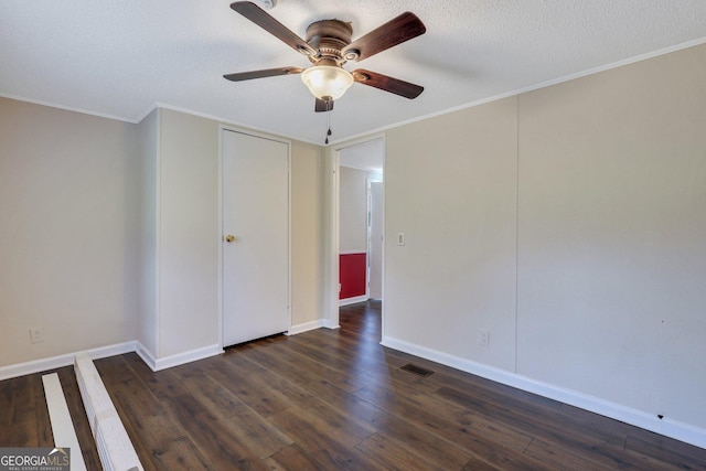 empty room featuring a ceiling fan, dark wood-style flooring, visible vents, crown molding, and baseboards