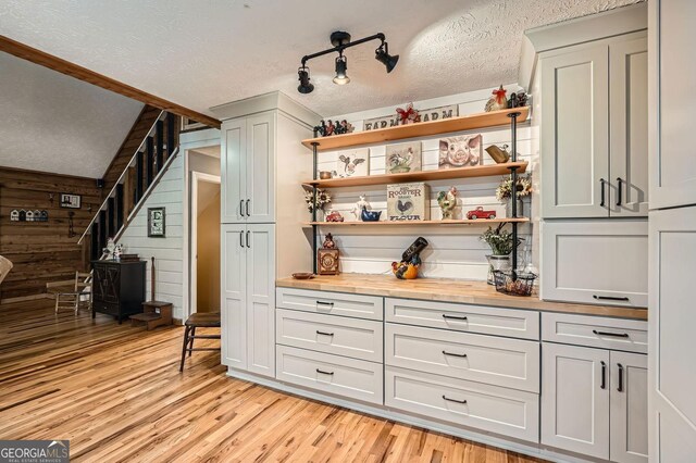 5419 Tyree Rd, Winston, GA 30187 - bar with light wood-style flooring, a textured ceiling, wooden walls, and a wood stove