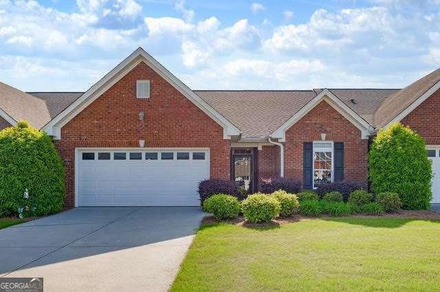 ranch-style house featuring brick siding, a front yard, and concrete driveway