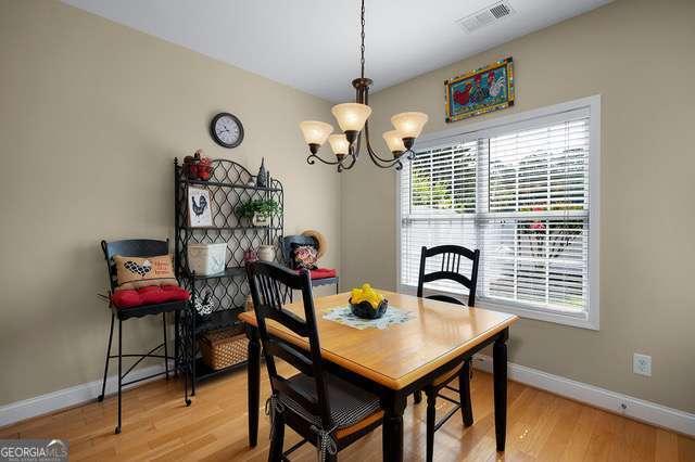 dining space with a chandelier, baseboards, visible vents, and light wood-type flooring
