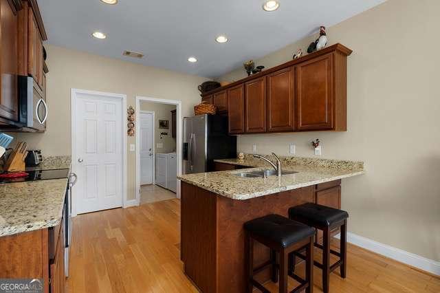 kitchen featuring a peninsula, washer and dryer, baseboards, a sink, and appliances with stainless steel finishes