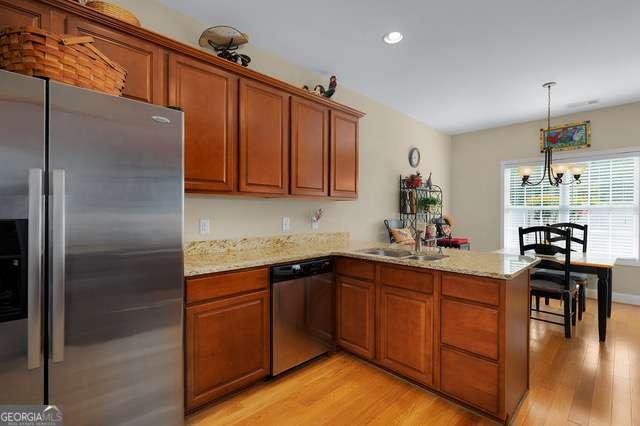 kitchen with brown cabinets, a peninsula, appliances with stainless steel finishes, and light wood-style flooring