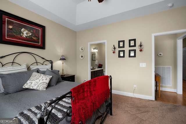 bedroom featuring baseboards, ensuite bathroom, carpet, and visible vents