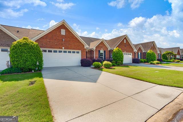single story home featuring a garage, driveway, a front lawn, and brick siding