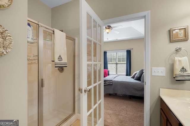 ensuite bathroom featuring ceiling fan, french doors, a shower stall, vanity, and connected bathroom