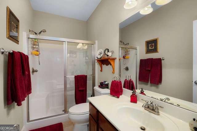 full bathroom with vanity, a stall shower, and toilet