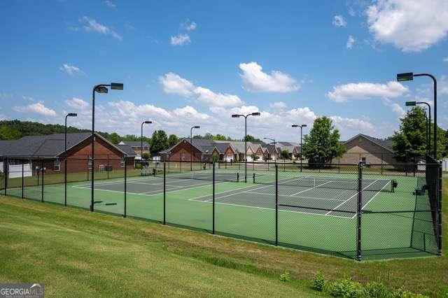 view of tennis court with a lawn and fence