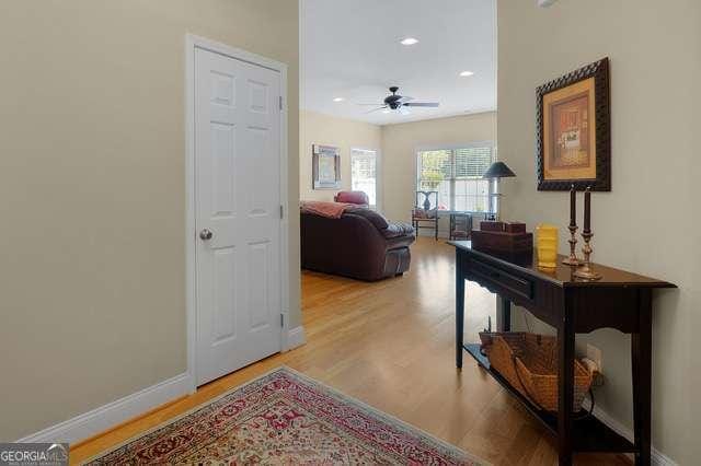 hall featuring baseboards, recessed lighting, and wood finished floors