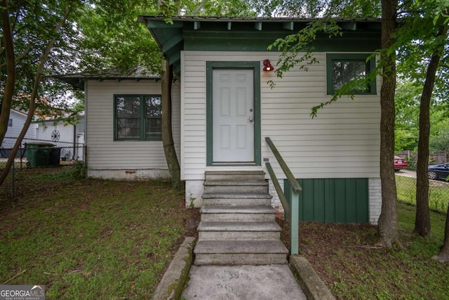 view of exterior entry with fence and crawl space