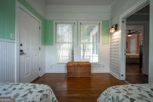 bedroom featuring a wainscoted wall, ornamental molding, and wood finished floors