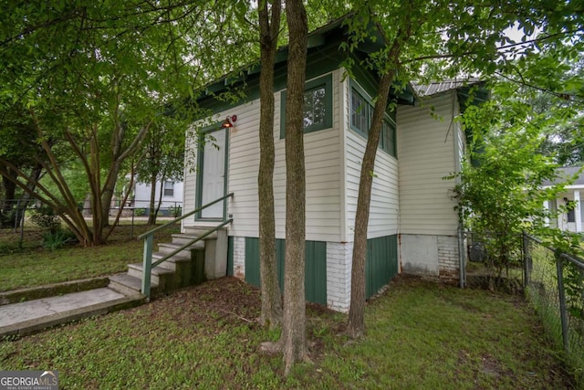 view of side of home with fence private yard, a yard, and entry steps