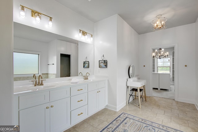 full bath with double vanity, baseboards, a chandelier, and a sink