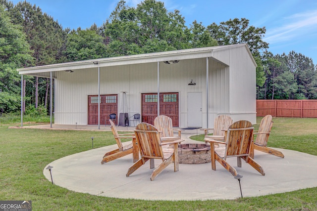 view of patio / terrace with fence, a fire pit, and an outbuilding
