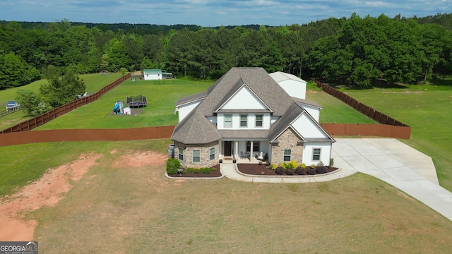 exterior space with a view of trees, a front yard, and stone siding