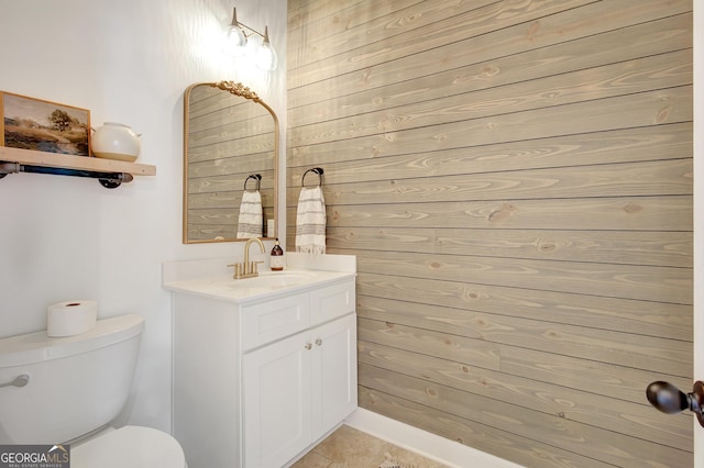 half bath with toilet, tile patterned floors, and vanity
