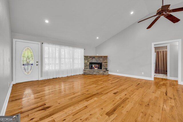unfurnished living room featuring high vaulted ceiling, a fireplace, a ceiling fan, and light wood finished floors