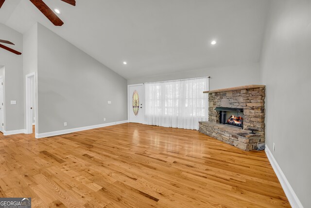 unfurnished living room with a ceiling fan, a fireplace, wood finished floors, high vaulted ceiling, and baseboards