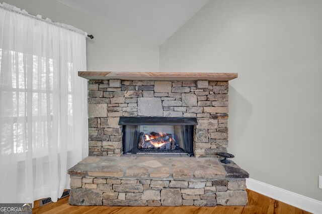 interior details with baseboards, a stone fireplace, and wood finished floors