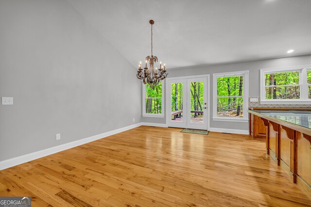 unfurnished dining area featuring an inviting chandelier, light wood-style floors, recessed lighting, baseboards, and lofted ceiling