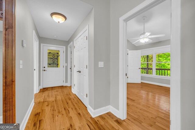 hall with light wood-style floors and baseboards