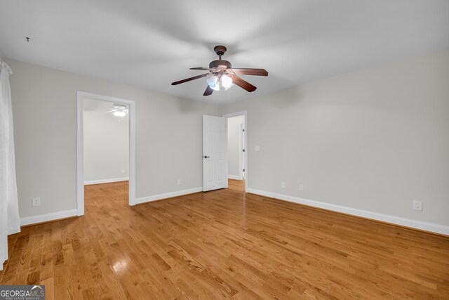 unfurnished bedroom with light wood-style floors, a ceiling fan, baseboards, and a spacious closet