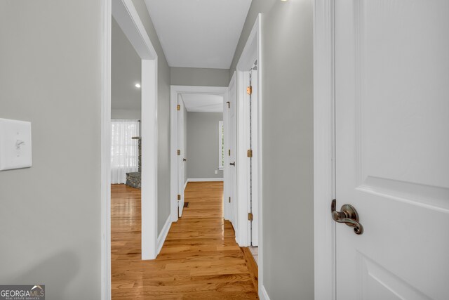 hallway with baseboards, plenty of natural light, and light wood-style flooring