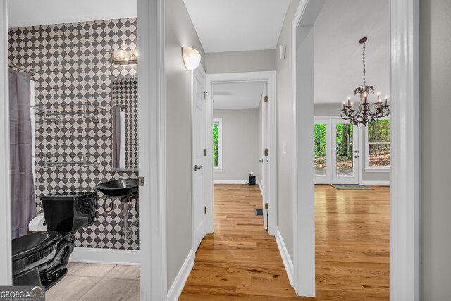 hall with an inviting chandelier, baseboards, wood finished floors, and a wealth of natural light