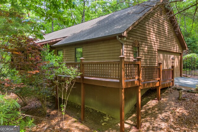 view of home's exterior featuring roof with shingles, a wooden deck, and a detached garage
