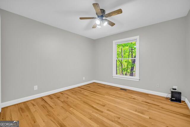 unfurnished room with baseboards, wood finished floors, and visible vents