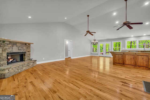 unfurnished living room featuring a fireplace, ceiling fan with notable chandelier, light wood-type flooring, and visible vents