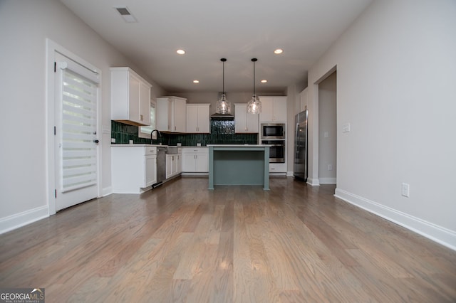kitchen with visible vents, white cabinets, tasteful backsplash, custom range hood, and stainless steel appliances