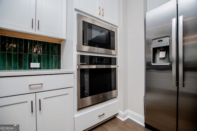 445 Boulder Crest Trl, Villa Rica, GA 30180 - kitchen with appliances with stainless steel finishes, light countertops, backsplash, white cabinetry, and dark wood-style floors