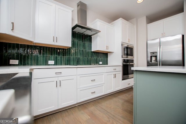 445 Boulder Crest Trl, Villa Rica, GA 30180 - kitchen featuring stainless steel appliances, exhaust hood, light wood-style floors, white cabinets, and tasteful backsplash