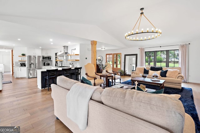 living room featuring ornate columns, recessed lighting, light wood-style flooring, and a chandelier
