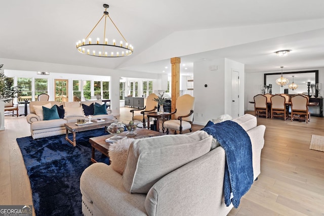 living room featuring an inviting chandelier, vaulted ceiling, light wood-style flooring, and a wealth of natural light
