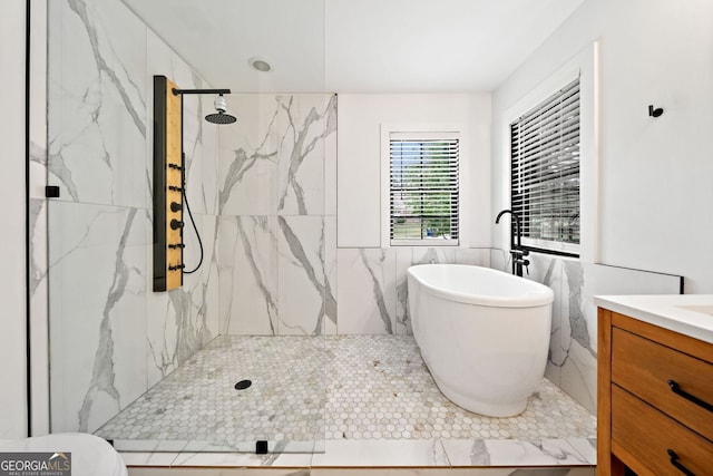 bathroom with a freestanding tub, a marble finish shower, vanity, and tile walls