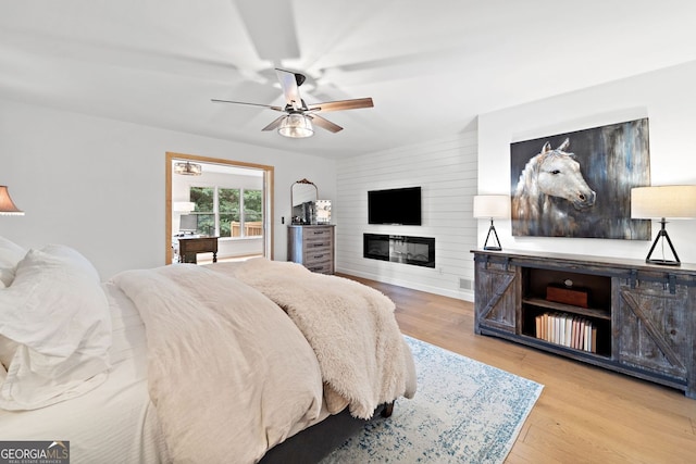 bedroom with visible vents, a ceiling fan, wood finished floors, and a large fireplace