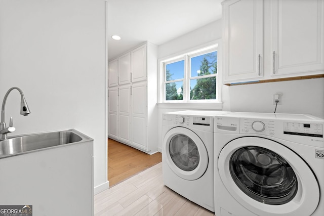 clothes washing area featuring cabinet space, a sink, light wood-style floors, recessed lighting, and washer and clothes dryer