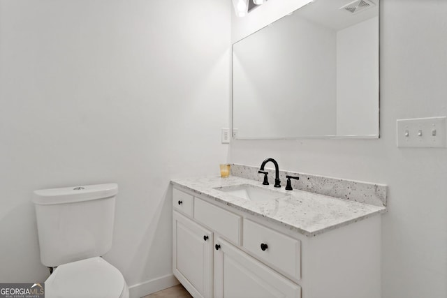 half bathroom featuring visible vents, baseboards, toilet, and vanity