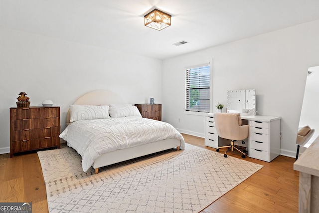 bedroom with baseboards, visible vents, and light wood finished floors