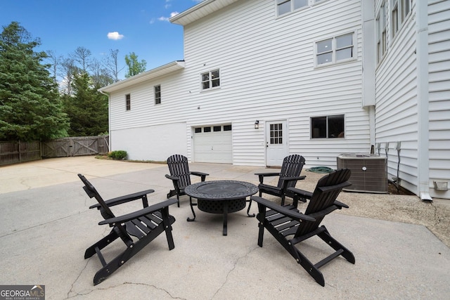 view of patio featuring fence, an outdoor fire pit, central AC, a garage, and a gate